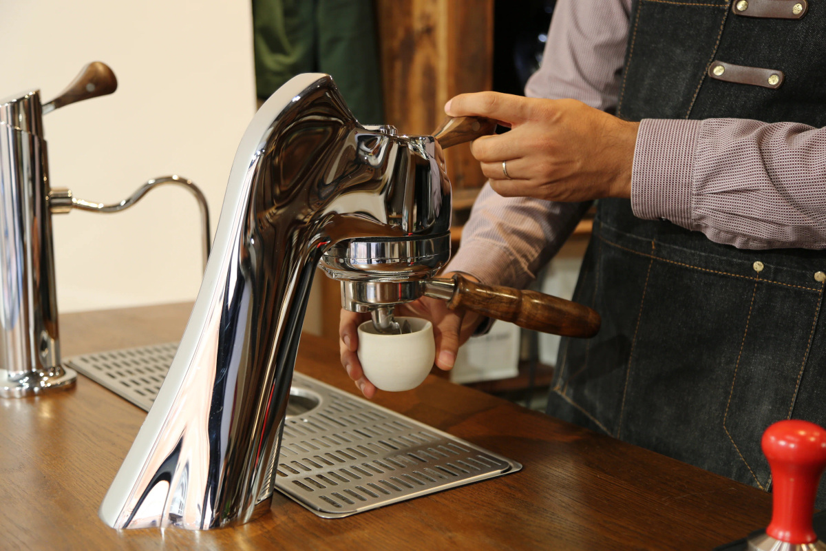 A barista serves an espresso at a wooden counter