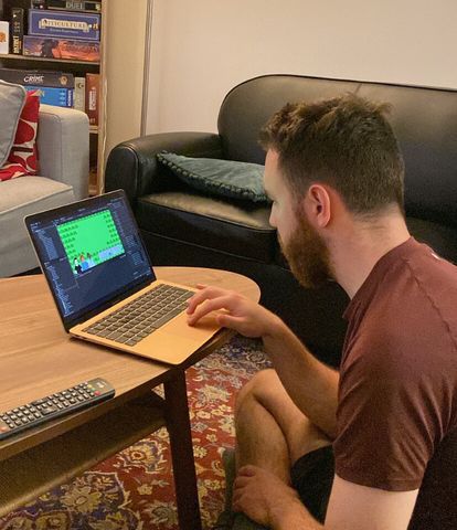 Myself sitting in the living room, working on "Power Up!" on a laptop, with board games visible in the background.